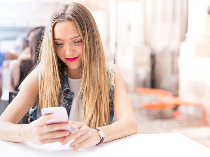 Pretty and happy blonde teenager outdoor with her mobile phone What Millennial Shoppers Want